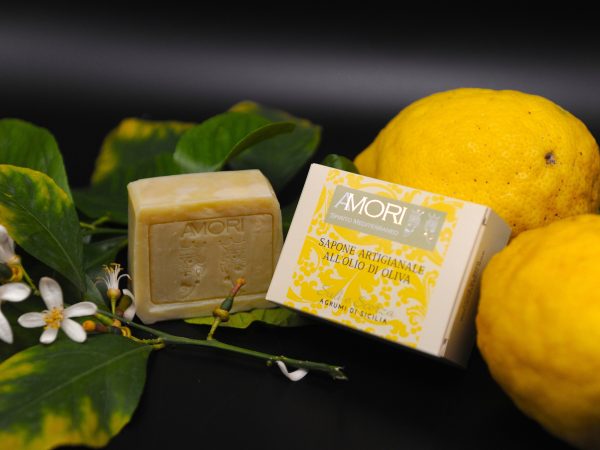 SULI E SCORZA Sapone artigianale all'olio di oliva al profumo di agrumi di Sicilia. Il nostro sapone è fatto secondo un’antica ricetta siciliana del 1800 tramandata di generazione in generazione. Produciamo seguendo il metodo a caldo, per conservare inalterate le proprietà del nostro puro olio di oliva. L’Olivo è il primo albero citato nella storia ed è uno dei più diffusi ed amati in Sicilia. Il suo olio è ricco di acido oleico (circa il 62%), con grandi proprietà nutrienti ed emollienti per la pelle. Le note fresche degli agrumi di Sicilia donano una sensazione di energia e leggerezza. Un gesto semplice, che rispetta la natura e si prende cura di te.